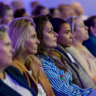 Deelnemers zitten in een zaal naar een lezing te luisteren