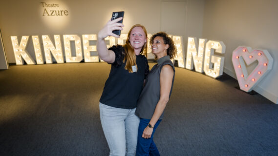 Deelnemers poseren voor de grote letters Kinderopvang en maken een selfie