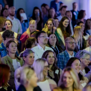 Mensen staan op uit hun stoel tijdens een lezing in een plenaire zaal