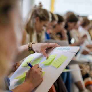 Deelnemer schrijf op een post it tijdens een workshop